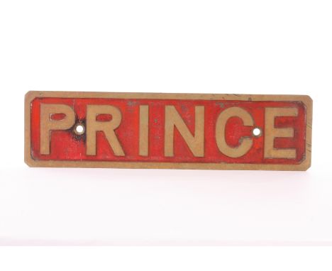 A cast brass nameplate ‘Prince’: the name appearing in raised brass letters against a weathered red background, green paint t
