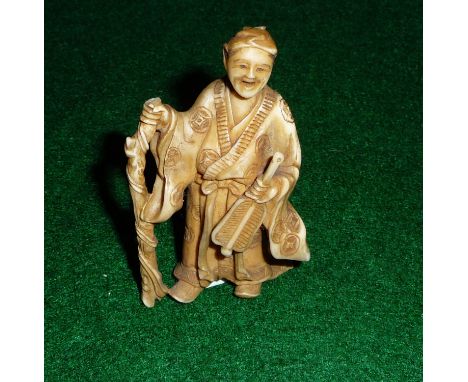 A small ivory figure of a man with walking stick