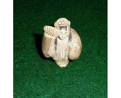 An ivory netsuke of a girl with fan