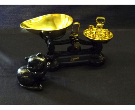 A pair of cast and brass weigh scales with weights and a cast iron cat door stop