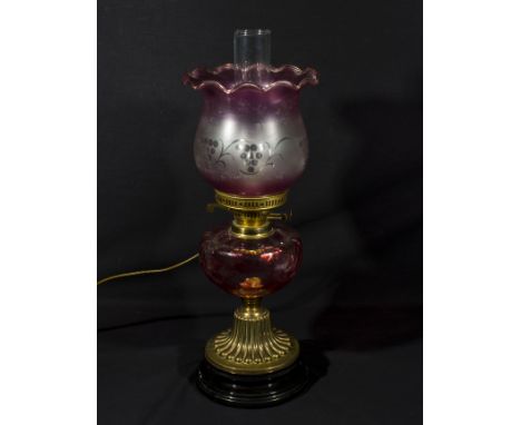A converted ruby oil lamp with shade and funnel