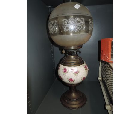 A vintage oil burning lamp with ceramic well and etched glass shade