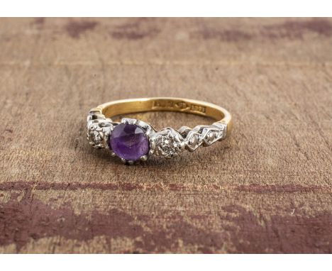 An 18ct and platinum three stone amethyst and illusion set diamond ring, the round claw set centre stone, flanked by two eigh