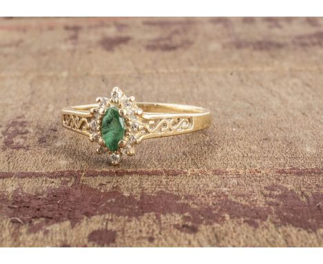 A continental 14K marked gem set cluster ring, the marquise cut emerald in claw setting, surrounded by a band of round cut di