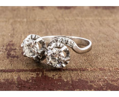 A diamond cross over dress ring, the two brilliant cuts, in claw settings, set above raised gallery with diamond set shoulder