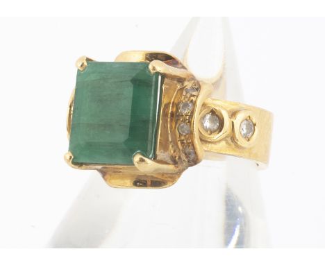 A continental emerald and diamond dress ring,  the mixed rectangular cut emerald in a claw setting with diamond set shoulders