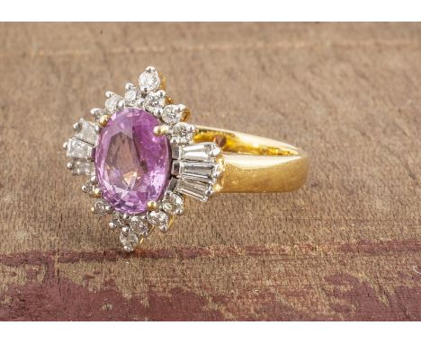 A pink sapphire and diamond cluster dress ring, the oval mix cut claw set pink stone, surrounded in baguettes and brilliant c