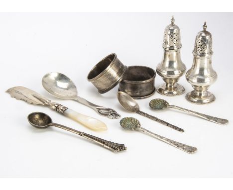 A small group of silver items, including a pair of peppers, a pair of napkin rings, a pair of shell salt spoons, a mop handle