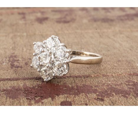 An 18ct marked white metal and diamond cluster ring, the brilliant cuts in claw settings, the central stone raised weighs app