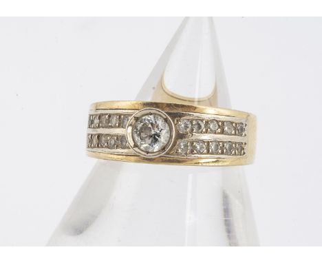 A continental yellow metal diamond and CZ dress ring, centred with a brilliant cut diamond, either side of channel set CZs,  