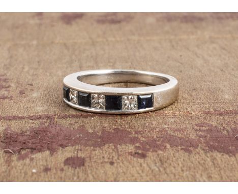 An 18ct white gold seven stone sapphire and diamond half hoop eternity ring, channel set square cut stones, in white gold hal