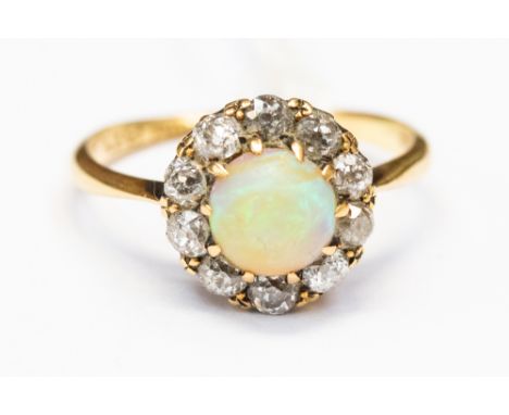 An opal and diamond cluster ring, set in 18ct gold, a round opal displaying green and orange fire, approx 6mm in size, with a