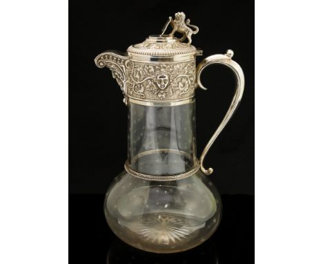 An Edwardian silver mounted glass claret jug, hte rim and lid embossed and chased with Bacchus head and foliate vine motifs, 