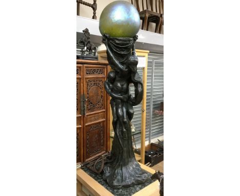 A European Art Nouveau bronzed floor standing lamp, modelled as two figures in an embrace and supporting an iridescent glass 