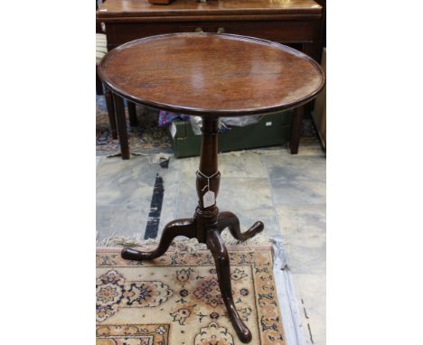 A George III oak tilt top tripod table, the top with a dished edge, raised on a turned base, three cabriole legs 