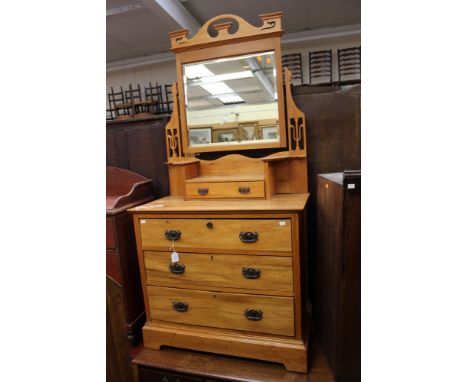 An Edwardian Art Nouveau dressing chest, with a mirrored back, the adjustable mirror with a drawer below, the base with three