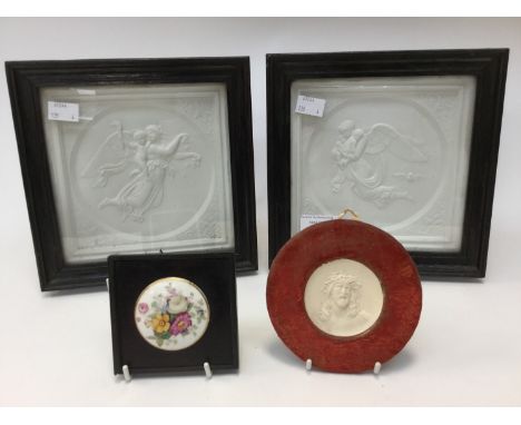 A pair of ceramic relief molded plaques depicting angels with children; together with a similar circular plaque depicting Jes