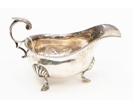  A George V silver sauce boat, plain oval shape with gardroon rim on three shell and hoof feet, C-scroll handle, Harrison Bro