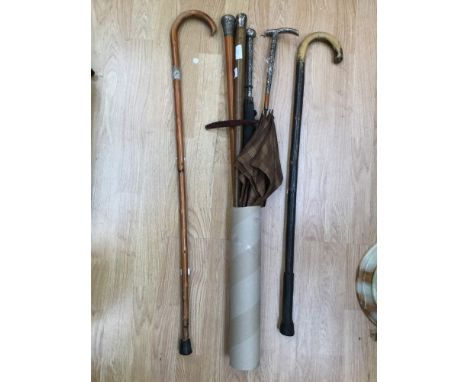 A collection of vintage umbrellas and walking sticks to include an Oriental umbrella and walking stick with white metal handl