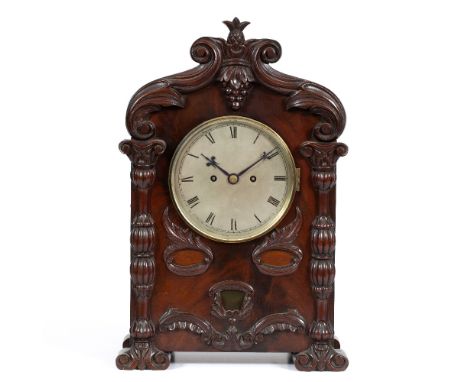 A VICTORIAN MAHOGANY TABLE CLOCK the arching case surmounted by a pineapple finial, further decorated with scrolls and carved