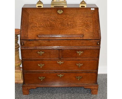 An Early 18th Century Oak Bureau, the fall enclosing a sliding well, pigeon holes and small drawers, the base of two short ov