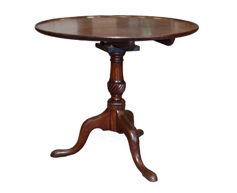 A George III Mahogany Fliptop Tripod Table, 3rd quarter 18th century, the circular dish top above a birdcage platform, on a b