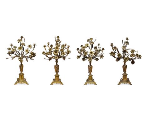 A Garniture of Four French Gilt Metal Candelabra, 19th century, each as an angel supporting an arrangement of flowering lilie