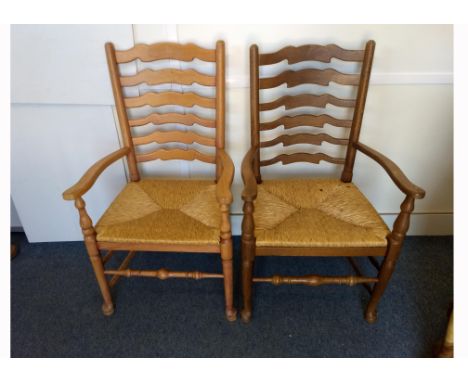 Two modern oak and rush-seated carvers chairs, shaped ladder backs, turned supports, pad and ball front feet (2)