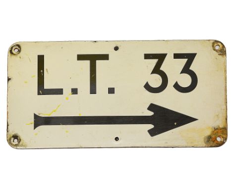 An enamel directional sign displaying 'L.T. 33',possibly for the Metropolitan Railway, above an arrow facing right, white gro