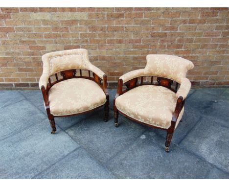 A PAIR OF EDWARDIAN ROSEWOOD FRAMED TUB CHAIRS  on turned supports with ceramic casters