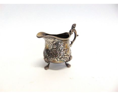 A GEORGIAN SILVER CREAM JUG makers mark rubbed, London 1815, chased with foliage, vacant cartouche, on three mask supports, d