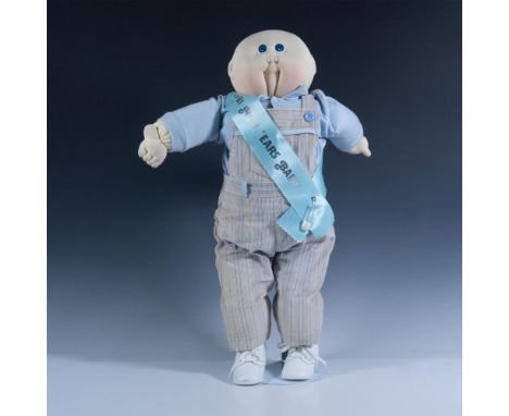 Features an adorable baby dressed in a jumper and blue sweater with a blue sash. Xavier Roberts signature stamp on shoe. Issu