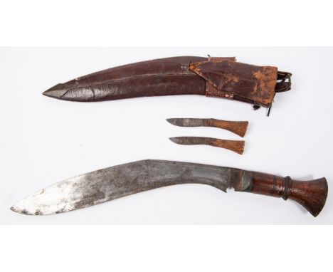 A kukri, blade 13½", marked "K B THAKURI &amp; SONS GHOOM DARJEELING", with plain wooden hilt and leather covered sheath with