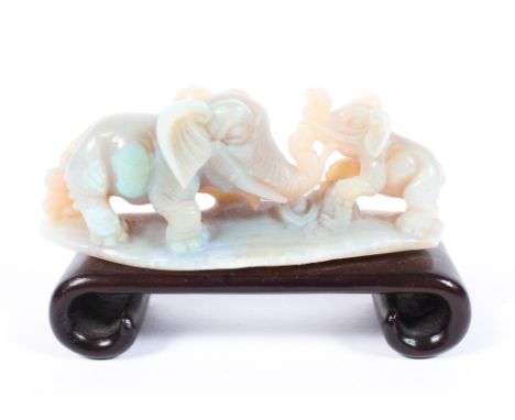 A Oriental carved opal model of an elephant and calf, mounted on a hardwood plinth stand. 9cm. 
