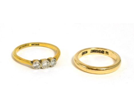 A diamond three stone ring, 0.20 carat approximately, finger size M, stamped 18ct and a 9ct gold band ring, finger size K (2)