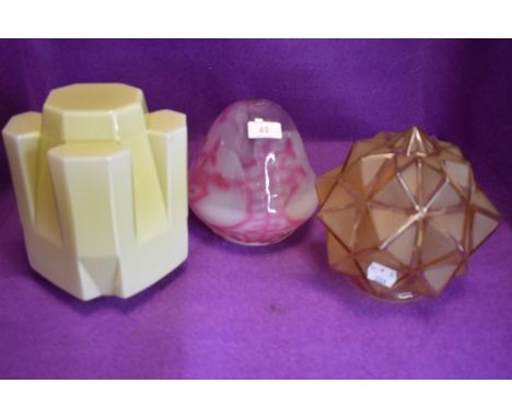 Three art deco glass lamp shades, one of mottled pink and white and another in yellow with angular design the last amber in c