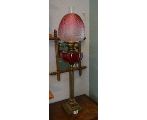 A Victorian brass column oil lamp with cranberry shade, 75cm high 