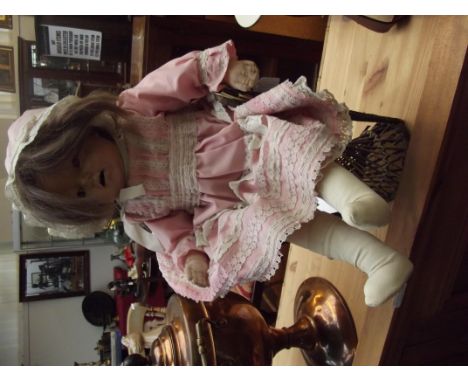 Early bisque headed doll, the head marked DPC, seated in wicker chair 