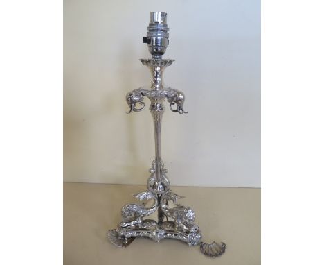 A silver plated table lamp of triform shape, with elephant and mythical beasts, 37cm tall, one broken corner piece, will need