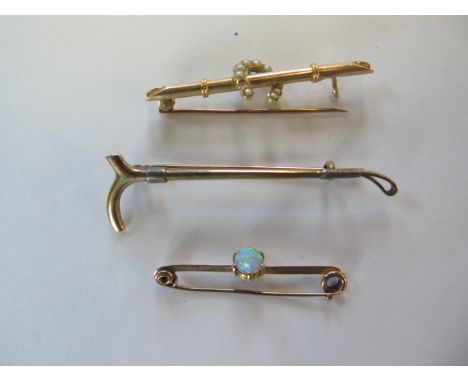 A 15ct gold riding crop brooch, approx 4 grams, and two gilt metal brooches, approx 4 grams, pearl missing to one brooch, and