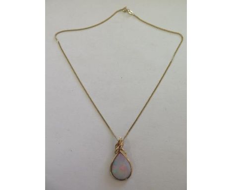 A large tear drop shape opal set in a yellow gold setting with clip back, measures 35mm x 20mm - pendant tested as 9ct gold, 