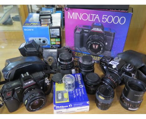 A collection of cameras, equipment and lenses including a Minolta 5000, Praktica EE2 and a bellows camera 