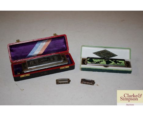 A boxed Hohner harmonica; another and two miniature harmonicas