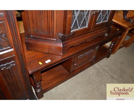 An oak old charm style low coffee table fitted with single cupboard and linen fold panel door