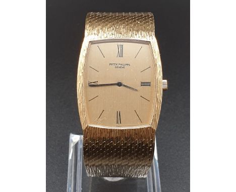 AN 18K GOLD PATEK PHILIPPE DRESS WATCH WITH SOLID GOLD BARKED STRAP. 28MM