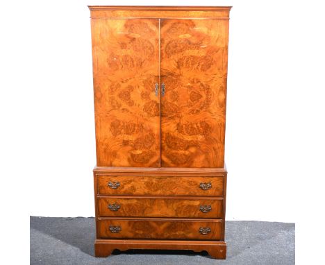 A reproduction figured walnut cabinet, two doors to the upper section enclosing shelves, three drawers under, bracket feet, w