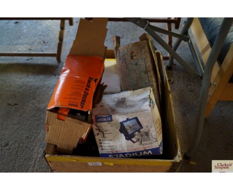 A box containing a stadium flood light; Black &amp; Decker circular saw attachment etc