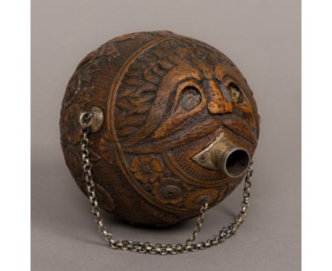 A 19th century carved coconut bugbear Of typical form, decorated in the round with trailing foliate designs, twin birds and m