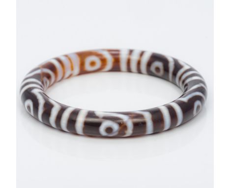 A Tibetan agate bangle Of typical form, with banded decoration. 8 cm diameter. CONDITION REPORTS: Generally in good condition