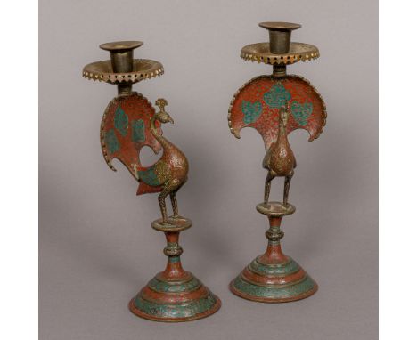 A pair of 19th century Indian brass candlesticks Each formed as a peacock with red and blue enamel decoration. Each 28 cm hig